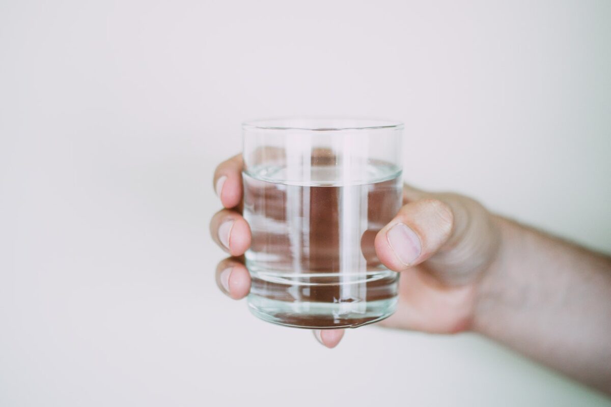 Which water filtration systems are the highest rated? A hand holds a clear glass of water against a white backdrop.